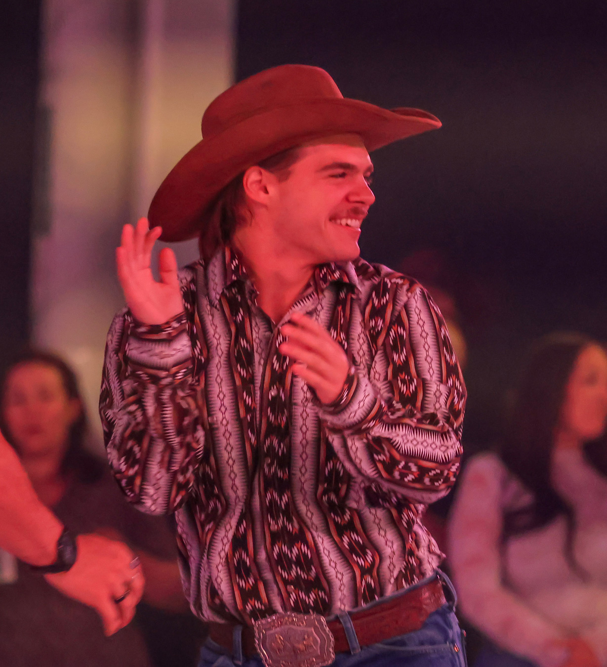 Danseur souriant portant un chapeau de cowboy lors d'une danse de country festive sur le circuit.